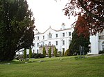 a large white house view across a lawn with trees