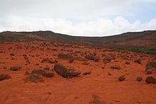 Peisaj de deșert format din bolovani și pământ roșiatic.