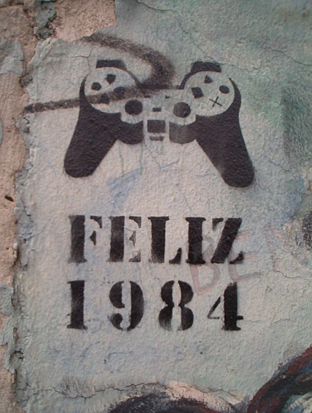 "Happy 1984" — Stencil graffiti found on the Berlin Wall in 2005. The object depicted is a DualShock video game controller.