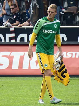 Foto van een man, voet, in voetbaloutfit, lopend met een voetbal keeperstrui en handschoenen