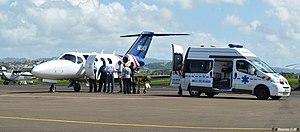 A patient is transferred between an aircraft and an ambulance at Le François airport.