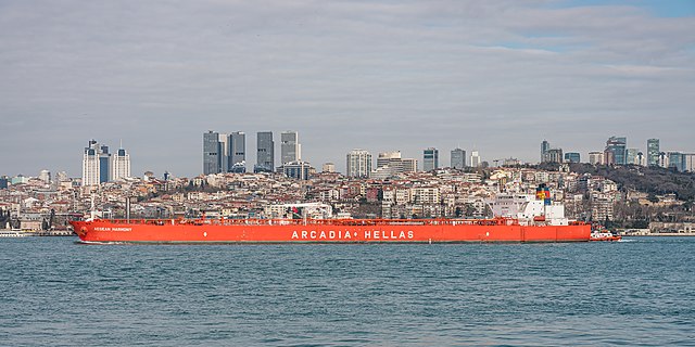 A large, low ship in front of a city skyline
