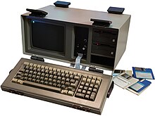 A Jonos Escort C2150 from 1983, next to a stack of 3.5-inch floppy disks. Jonos was the first company to ship a computer with 3.5-inch floppy drives. Jonos-table-photo edit.jpg