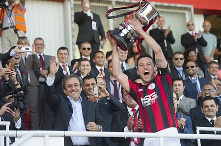 Lincoln Red Imps Captain Lifting 2014 Rock Cup from Michel Platini.jpg