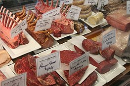 Numerosi tipi di carne in esposizione con etichette in salumeria