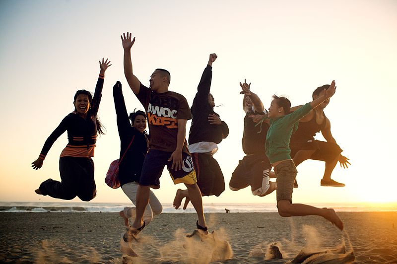 File:People jumping on the beach.jpg