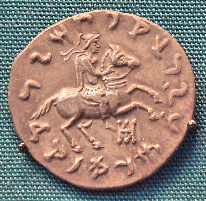 Coin of Philoxenus, making a blessing gesture with his right hand. Kharoshti legend MAHARAJASA APADIHATASA PHILASINASA "Invincible King Philoxenus". British Museum.