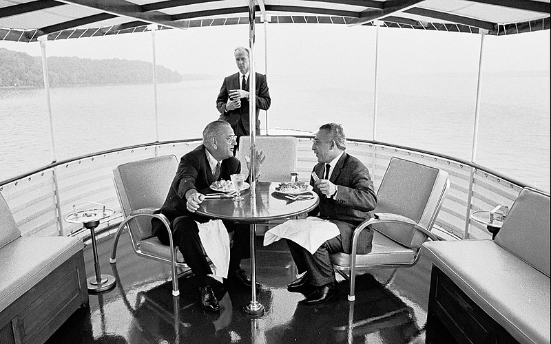 File:President Johnson has dinner with guest aboard the Sequoia as Secret Service Agent Rufus Youngblood stands in the background, July 15, 1965.jpg