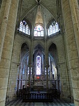 Chapelle contenant quelques chaises et présentant des verrières bleutées et noircies, surmontée de trois vitraux décoratifs et d'un vitrail figuré dont on ne peut voir les détails.