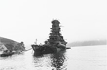 Japanse kruiser bij de haven, die water van achteren neemt.