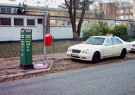 A taxi rank denoted by the green "taxi-calling post" (Taxenrufsäule)