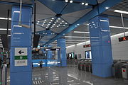 Station concourse with escalator and steps to platforms in the background