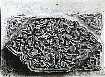 Relief yang menampilkan monyet yang telah distilir dengan daun-daun yang mengelilinginya