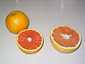 Снимка на Cara Cara портокал (вляво) с розов грейпфрут за сравнение на размер и цвят.