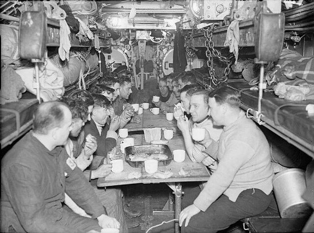Some of the Royal Navy crew of Graph having supper in the forward torpedo room during sea-trials, February 1942