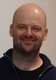 A bald middle-aged man smiling at the camera.