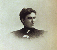 B&W portrait photo of a young woman with her hair in an up-do wearing a dark blouse.