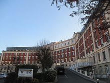 Photographie de la façade imposante, en brique rouge, d'un hôpital.