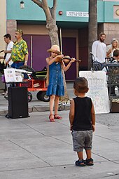 Photographie couleur d'une fillette jouant du violon dans une rue.