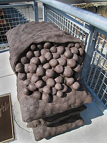 Four 50 lb burlap sacks of potatoes, made of cast stone, recall the massive potato sheds along Millers River that burned in 1962. Monument honoring former potato storage sheds.jpg