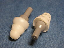 Musicians' earplugs. The grey end caps contain an acoustic transmission line with a damper (attenuator) at the end while the domed flanges form a seal in the ear canal. The output port can just be seen as a small hole at the near end of the left plug Musicians earplugs.jpg