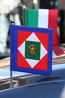 The Italian national colours, in the shape of an Italian flag and the standard of the president of the Italian Republic, on the presidential Lancia Flaminia. Their presence indicates that the president is on board. Presidente a bordo (1343751042).jpg