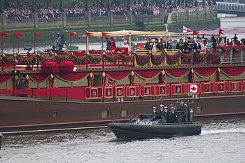 Social stratification. Prince William and Catherine, Duchess of Cambridge, aboard the royal barge during the 2012 Diamond Jubilee celebrations for Queen Elizabeth II. Social stratification is physicalised in the distance between the royals on the boat and public on the River Thames' bank.