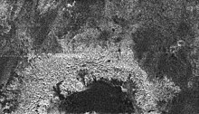 Radar image of a 139 km-diameter impact crater on Titan's surface, showing a smooth floor, rugged rim, and possibly a central peak. Titancrater.jpg