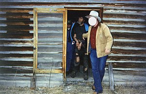 Photograph of a handcuffed Kaczynski being led from a cabin by a man