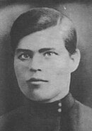 Portrait photograph of a young Nestor Makhno wearing a dark suit and neatly combed hair