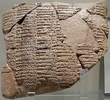 Photographie d'un assemblage d'une douzaine de fragments d'une tablette d'argile gravée d'écriture cunéiforme.