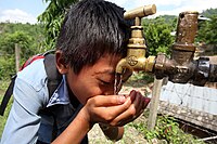 Boy drinks from a tap at a NEWAH WASH water project in Puware Shikhar, Udayapur District, Nepal. (10677903803).jpg