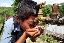 Boy drinks from a tap at a NEWAH WASH water project in Puware Shikhar, Udayapur District, Nepal. Boy drinks from a tap at a NEWAH WASH water project in Puware Shikhar, Udayapur District, Nepal. (10677903803).jpg