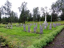 Colour photo of a small graveyard with about 40 dark grey gravestones