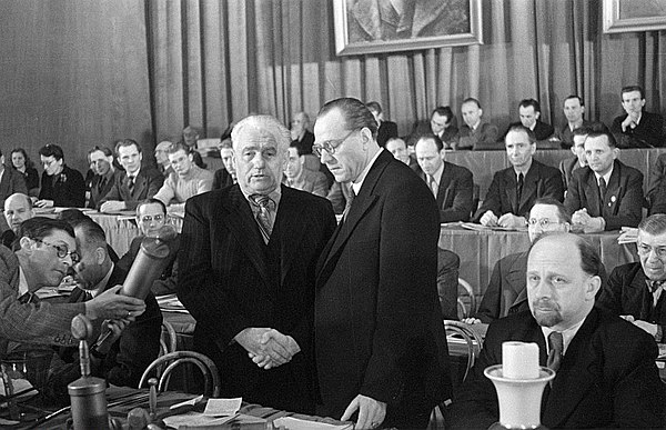 21 April 1946: Otto Grotewohl (right) and Wilhelm Pieck (left) seal the unification of the SPD and KPD with a symbolic handshake. Walter Ulbricht is seated in the foreground to the right of Grotewohl.Avraham Pisarek