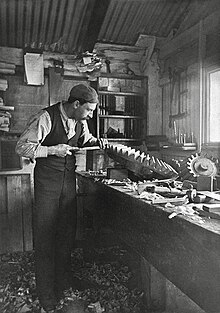 Man in a tin shed finishing a large precision wood carving that will be cast in his iron foundry