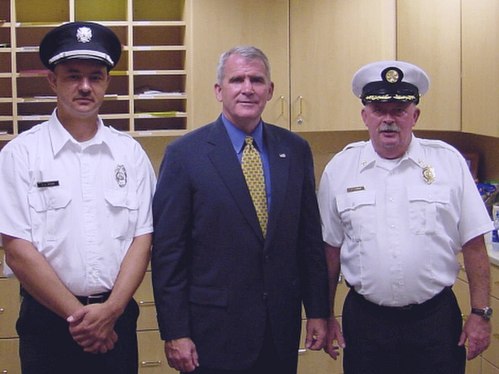 Oliver North in 2005, pictured with Clinton Township, Franklin County, Ohio Assistant Fire Chief John Harris and Lieutenant Douglas Brown, at a public