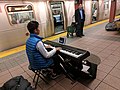 Piano-busking kid watches TV to entertain himself, subway platform, New York City, NY, USA (32300049594).jpg
