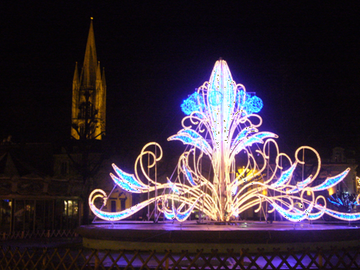 La fontaine illuminée pour les fêtes de fin d'année, avec en arrière-plan l'église Saint-Pierre-du-Queyroix