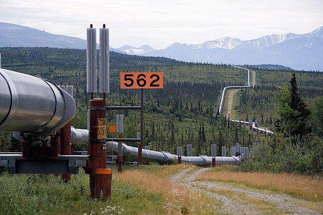 Oil pipeline winding through cold Alaskan country-side. In the background are mountains, partly snow-capped