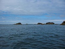 An image of the Western Rocks referenced by the article, particularly the infamous “Gilstone.” It appears as three almost iceberg-looking rocks shooting out in the distance over the Atlantic.