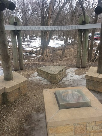The Wokiksuye K'a Woyuonihan memorial site at Fort Snelling, with a pipestone encased in the center, surrounded by bundles of the four sacred medicines: sage, cedar, tobacco, and sweetgrass.