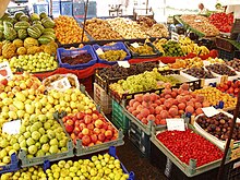 Dozens of baskets of brightly colored fruits and vegetables stacked around intersecting aisles at a market.