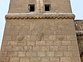 Vista de la torre oriental, con motivos de escudos tallados e inscripción superior.