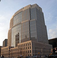 Vue extérieure d'un grand bâtiment beige avec de nombreuses fenêtres.