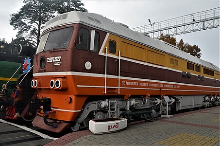 Diesellocomotief TEP80-0001 in oranje kleur, dicht bij de fabriek