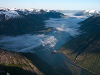 River and clouds flowing between two snow-capped mountain ranges