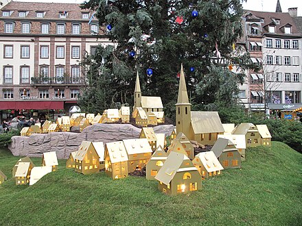 Enlighted house models at the foot of the tall Christmas tree in Strasbourg, France