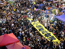 Manifestantes de Hong Kong segurando uma faixa dizendo "Eu quero um verdadeiro sufrágio universal".