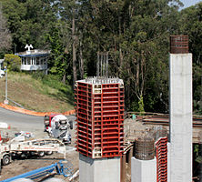 Column formwork: A monolithically cast column (formed in a single concrete pour) with its segmented metal formwork being disassembled from the bottom up.